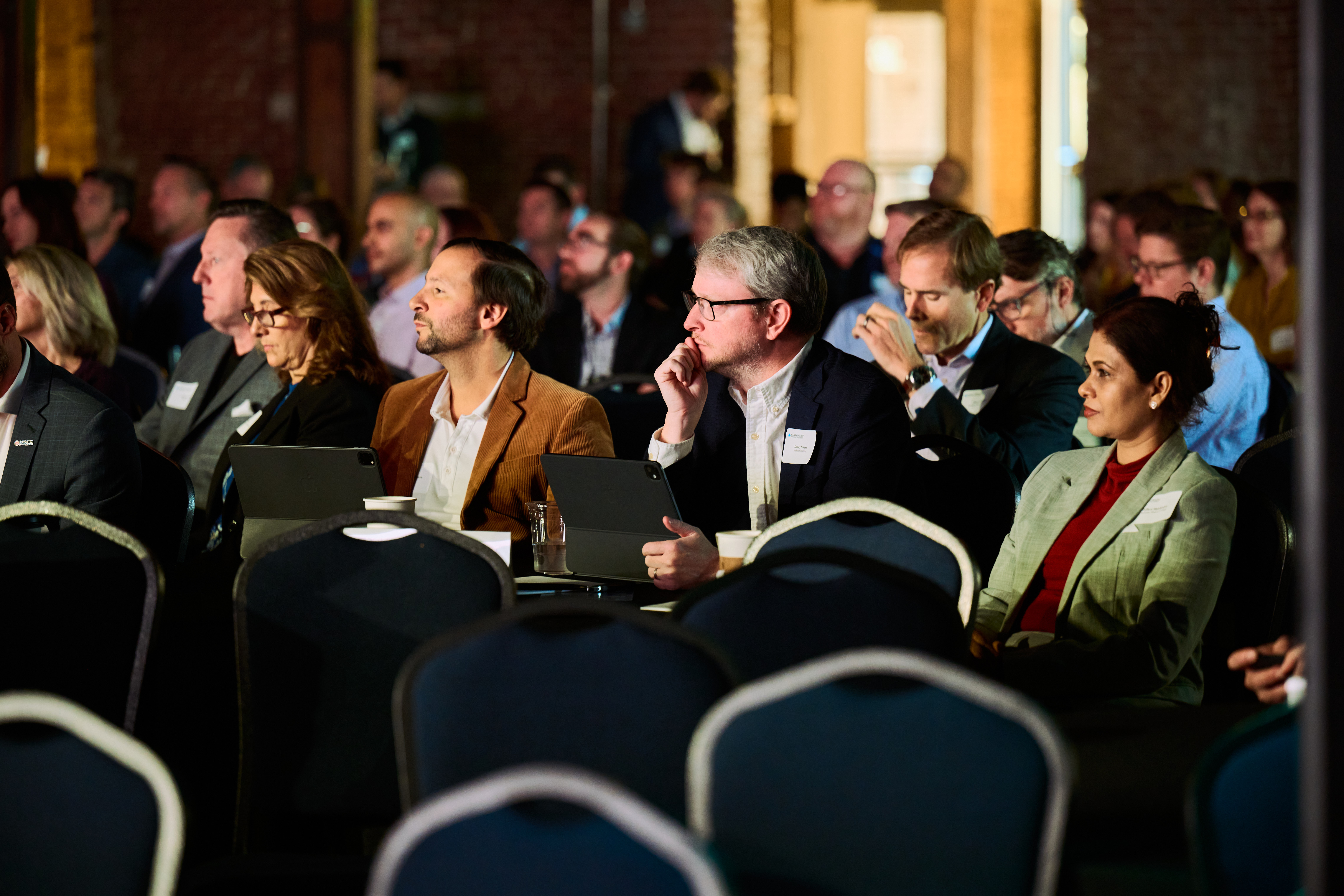 Engaged professionals seated in navy chairs at this year's Global Health Innovators Summit conference