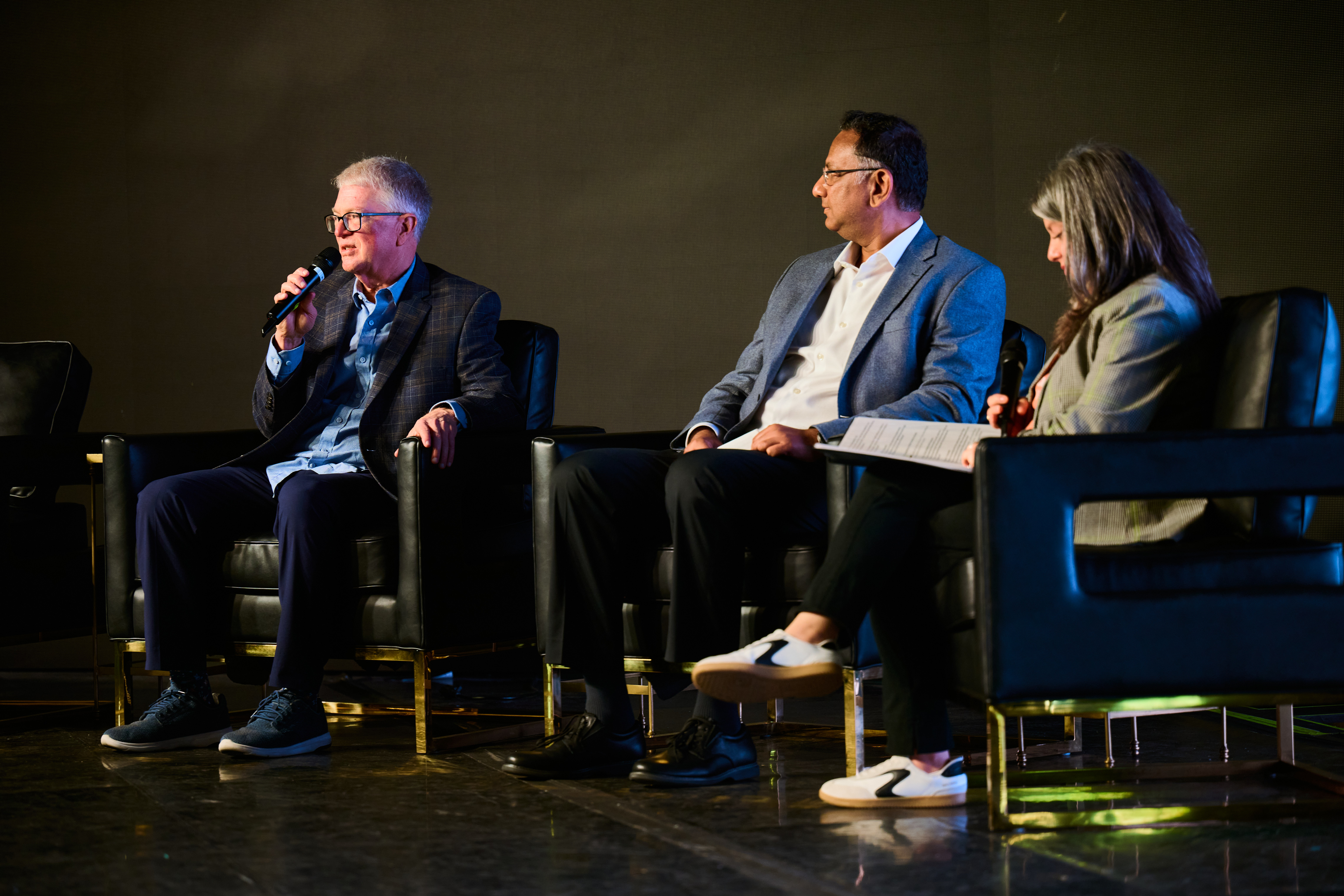 Panel discussion with three panelists seated on black chairs - Global Health Innovators Summit